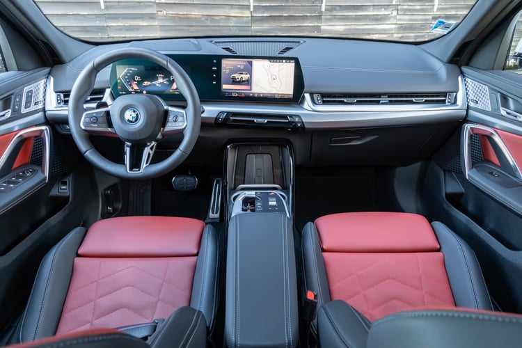 Planche de bord de la BMW iX2 avec écran incurvé Curved Display et sièges sport rouges et noirs