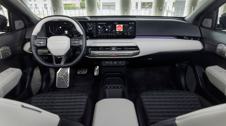 Planche de bord de la Kia EV4 avec triple écran panoramique, volant multifonctions et éclairage d’ambiance.