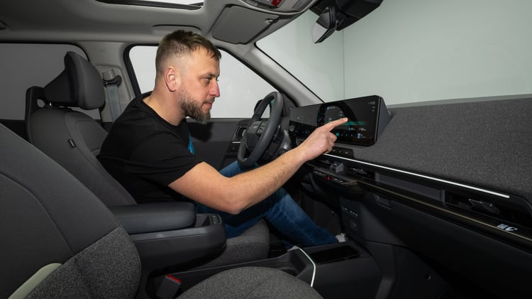 Conducteur utilisant l’écran panoramique de la Kia EV2 dans un habitacle au design épuré.