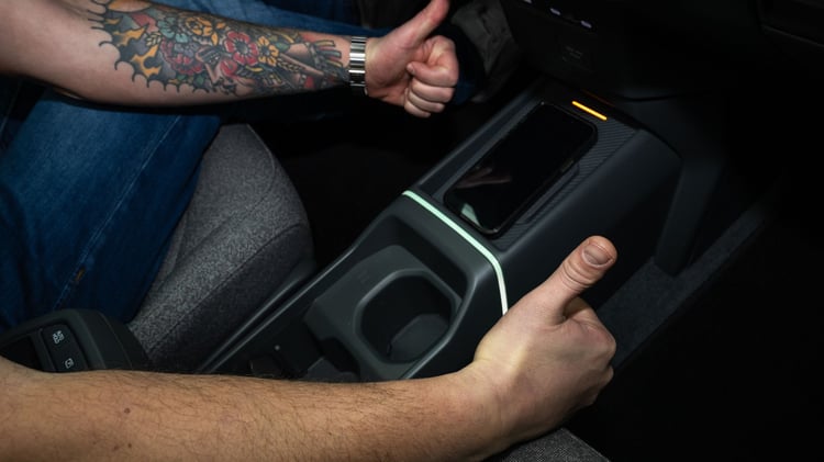 Console centrale de la Kia EV2 avec rangement pour smartphone, porte-gobelets et éclairage d’ambiance.