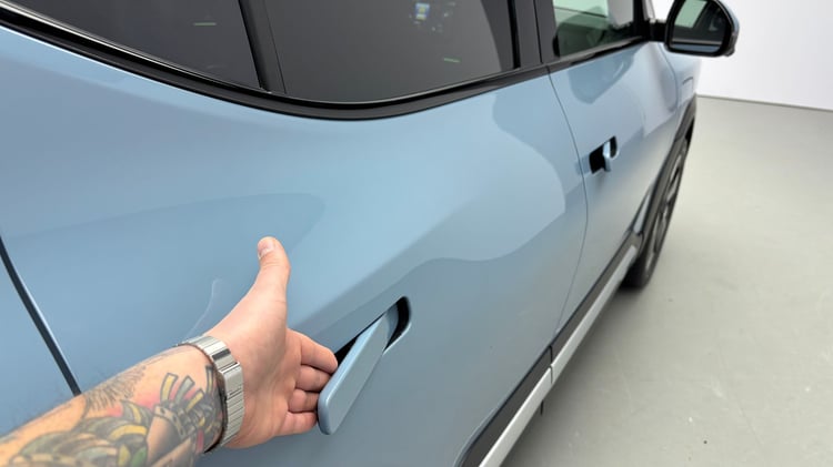 Poignée de porte intégrée de la Kia EV2, tirée à la main sur la carrosserie bleue.