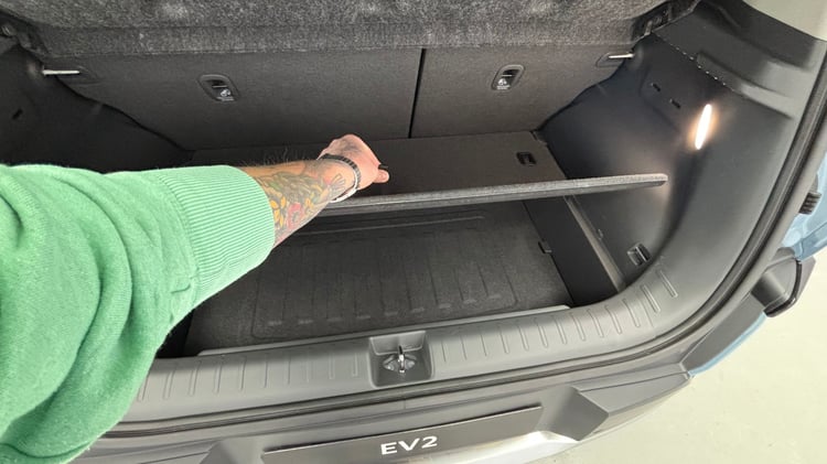Coffre de la Kia EV2 avec tablette cache-bagages et éclairage latéral.