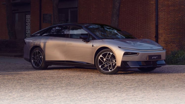 XPeng P7+ grise vue de trois quarts avant, berline électrique stationnée devant un mur en briques