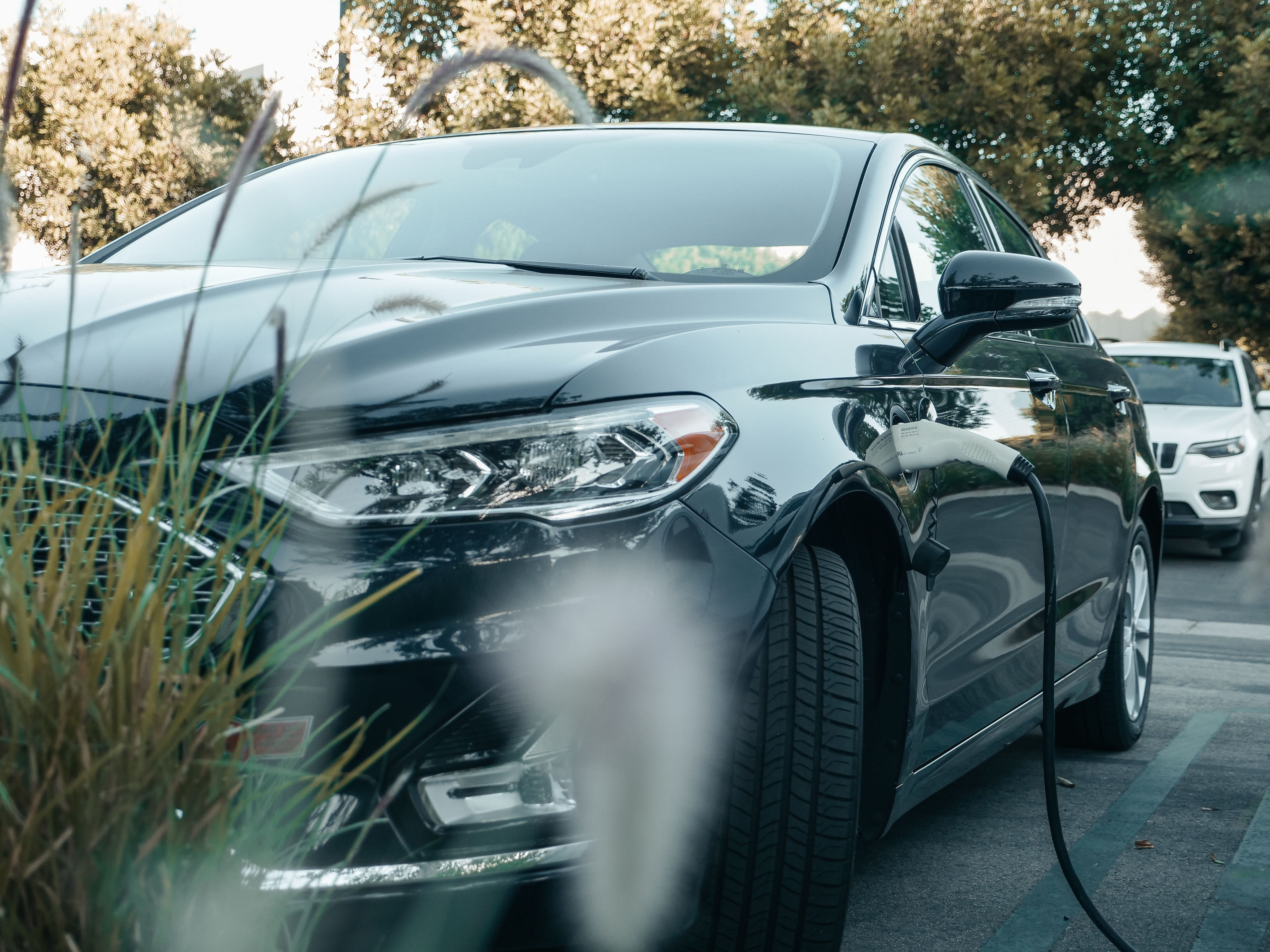 Berline électrique noire en recharge, câble branché sur la prise latérale du véhicule